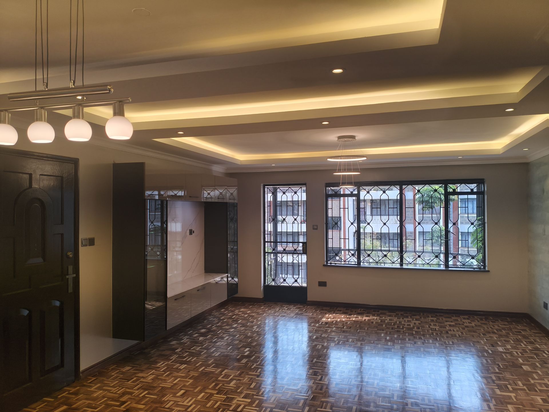 Living space with tray ceiling lighting and built-in cabinetry