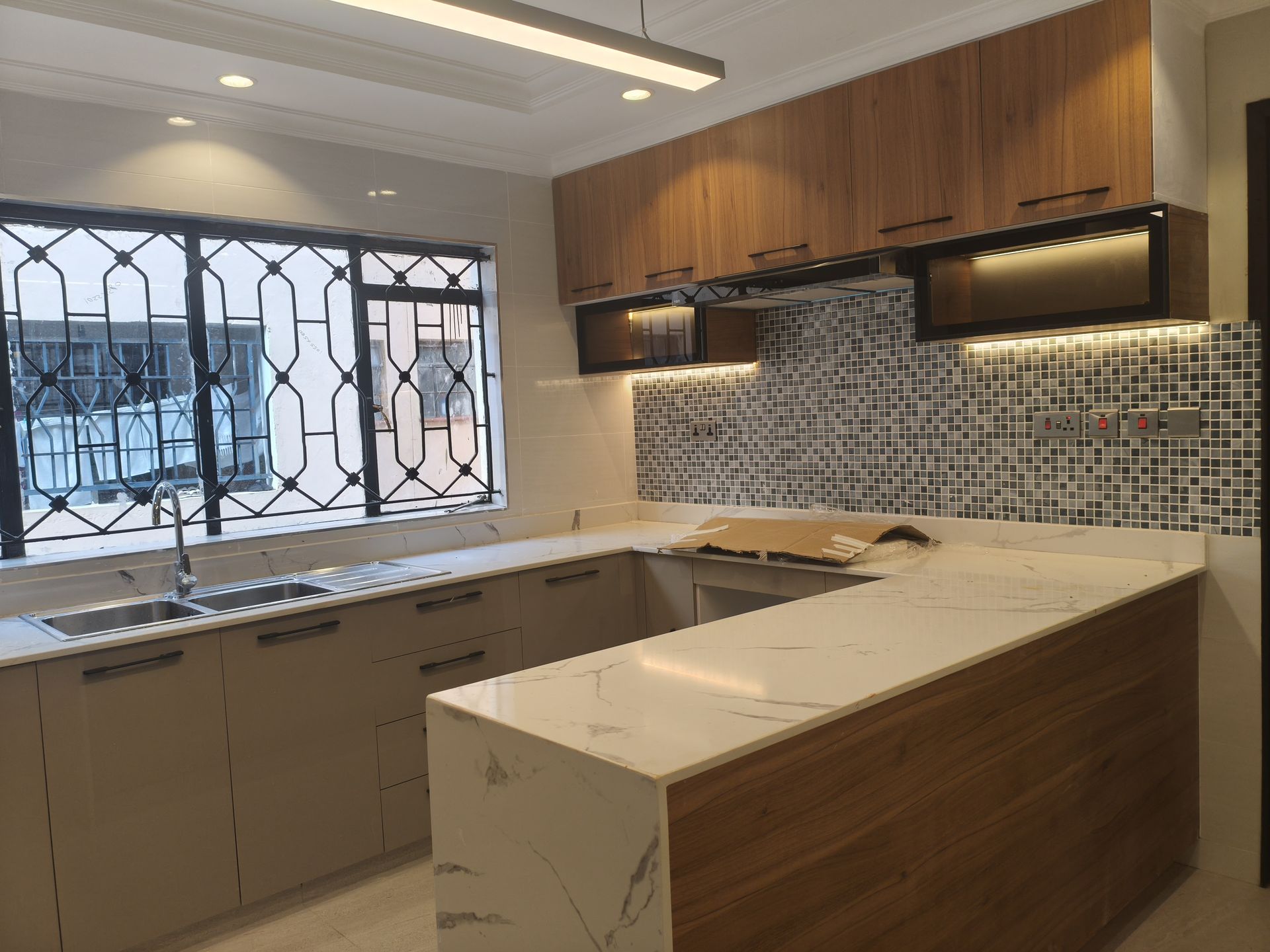 Marble kitchen island with wood cabinets and mosaic backsplash