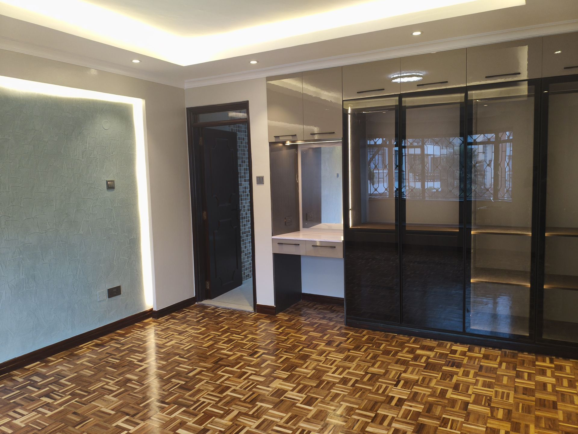 Dressing room with lit glass wardrobes and parquet floor