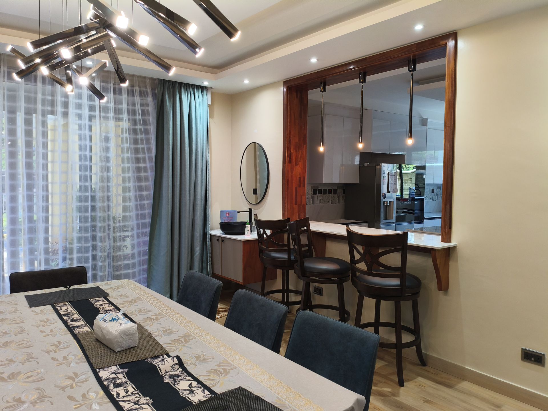 Open dining and kitchen with teal chairs and pass-through bar
